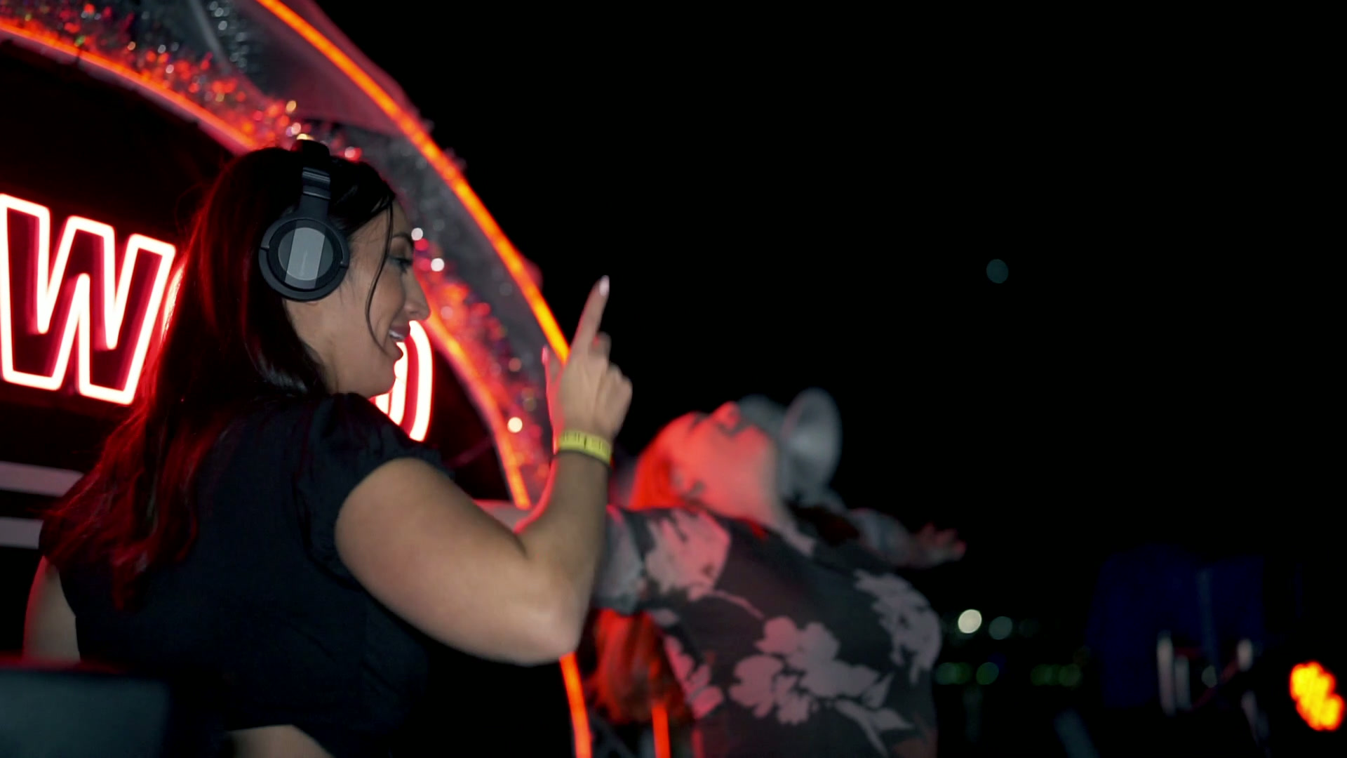 DJ set in a venue lit with a red neon sign